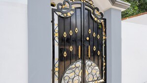 A black metal gate with ornate gold accents and a stone base. - FabHotel RB Palace - Nr. Varanasi Junction (Cantt) Railway Station (Varanasi)