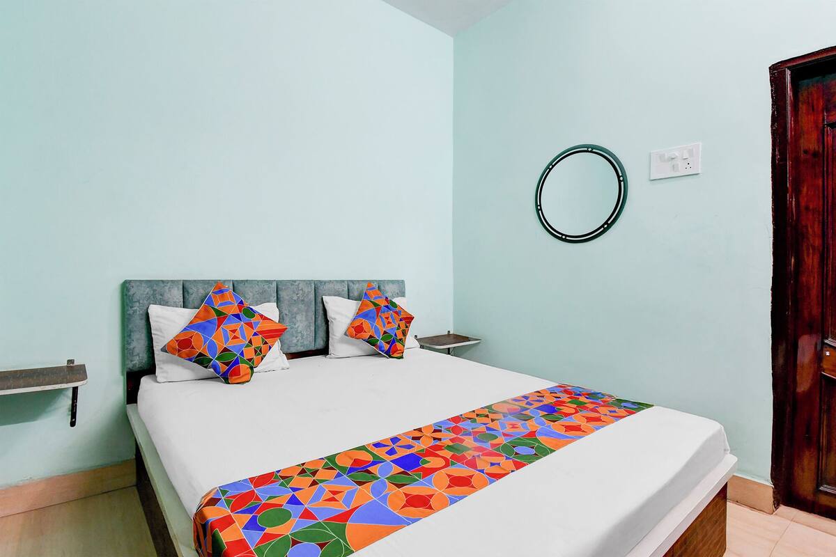 A bed with a colorful geometric-patterned blanket, a headboard, and two pillows with a similar pattern.