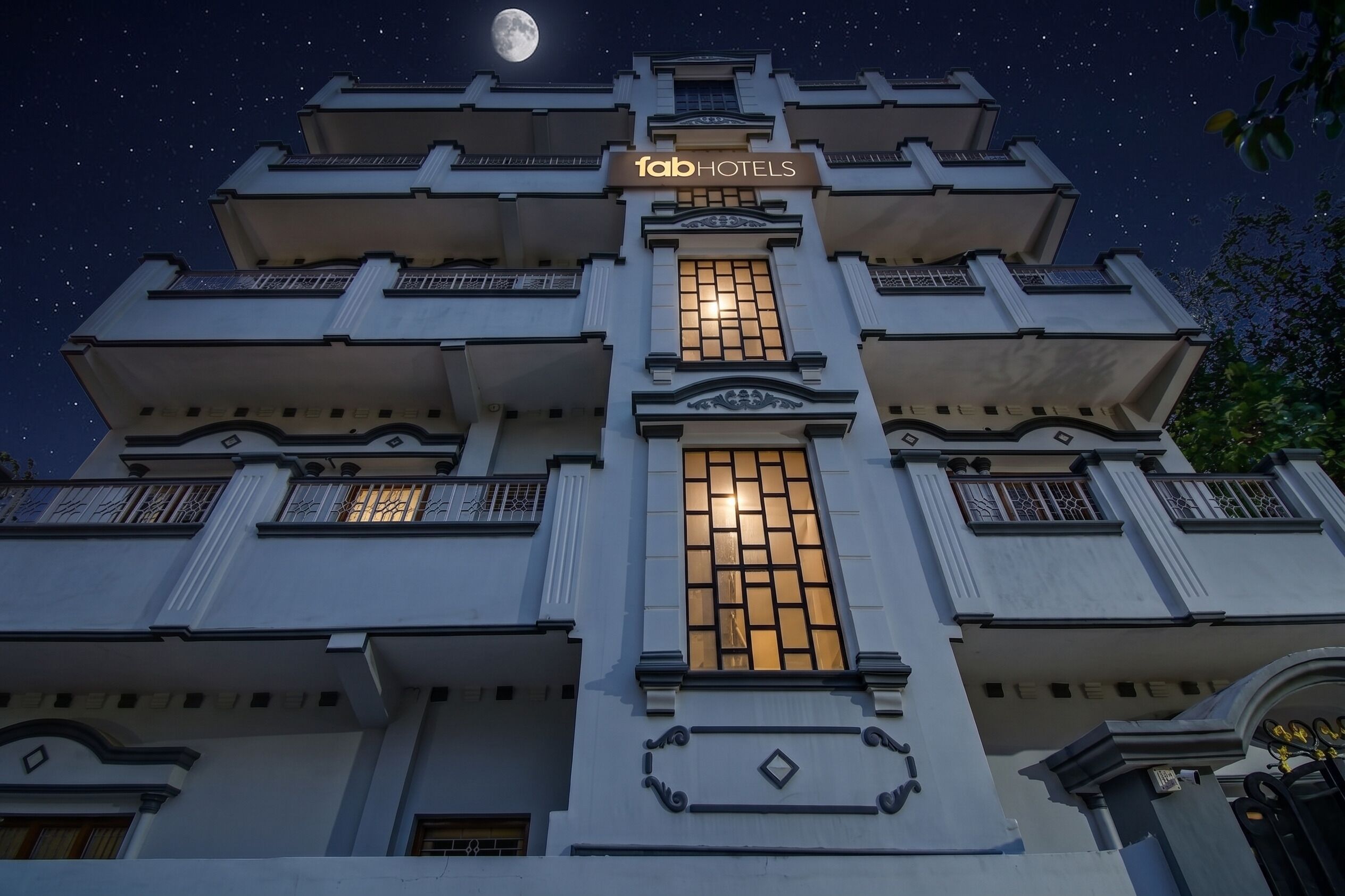 Un immeuble à plusieurs étages, reconnaissable à son grand panneau « fabHOTELS », à ses larges fenêtres et à son balcon.