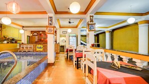 A hotel lobby with a pool area, seating arrangements, and a staircase leading to upper floors.