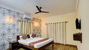 A bedroom with a wooden bed, patterned wallpaper, a ceiling fan, an air conditioning unit, and curtains.