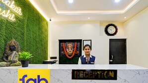 A reception desk with a 'fab hotels' logo, a clock, and a statue on the left. - Fabhotel Padmakar Kashi (Varanasi)