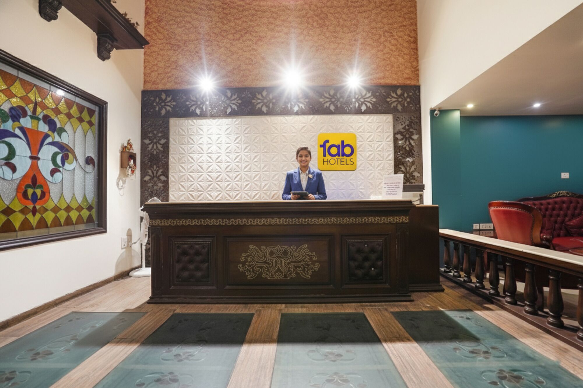 A hotel reception desk with a 'fab hotels' sign, a receptionist, and a patterned wall.