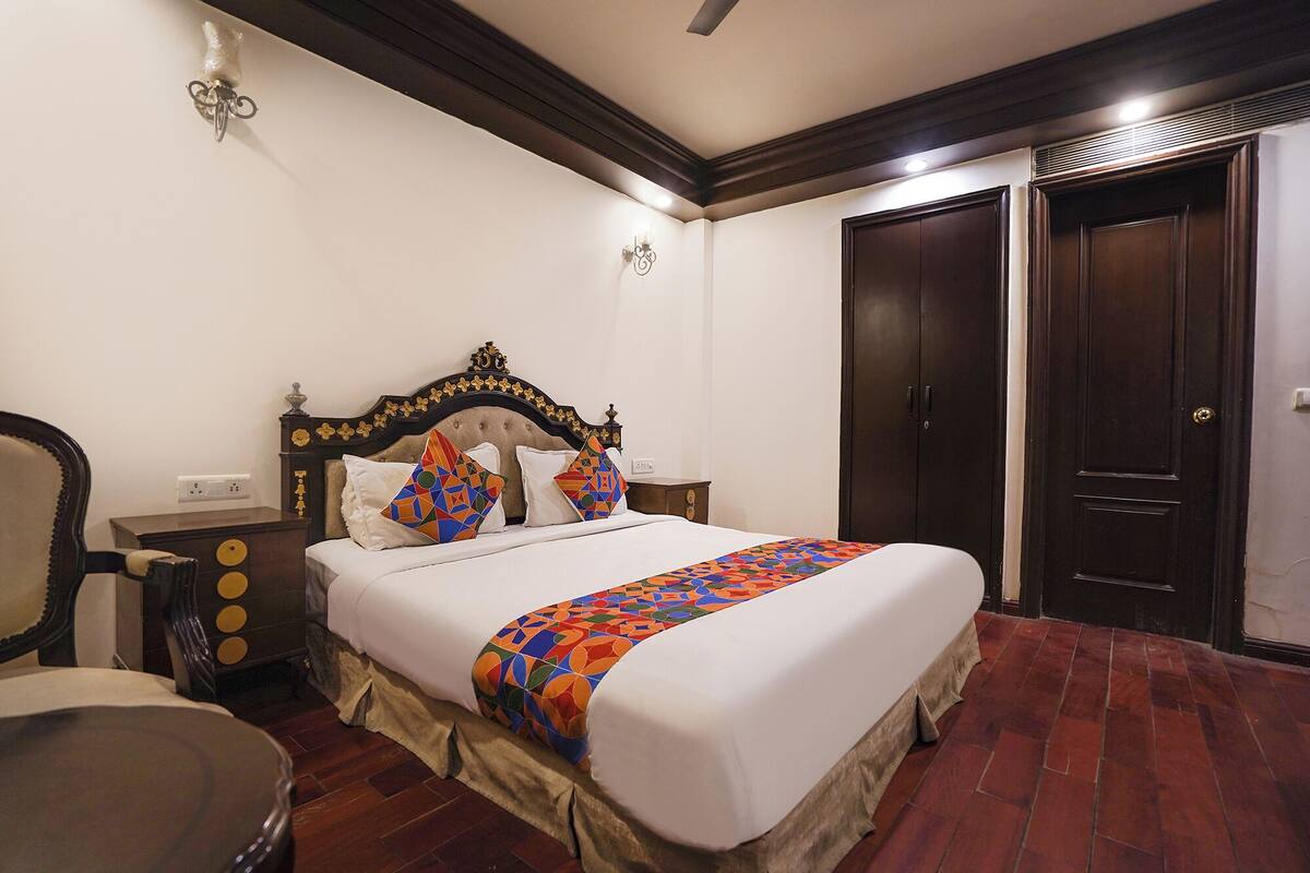 A neatly arranged bedroom with a large bed, a wooden headboard, a nightstand, a chair, and a wardrobe.
