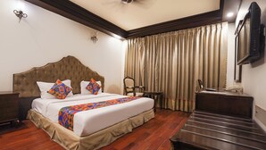 A hotel room with a tufted headboard bed, a wooden floor, a desk with a telephone, and a television on the wall. - Fabhotel Nfc Royale (New Delhi)