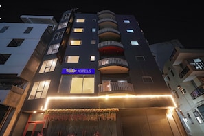 A multi-story building with a 'fabHOTELS' sign, balconies, and a decorative floral arrangement at the entrance. - Fabhotel Royale 49 (Noida)