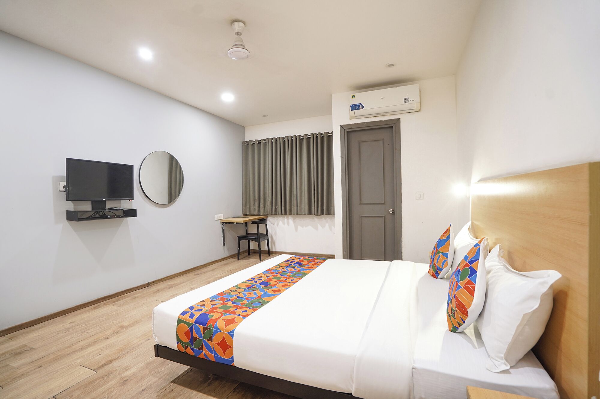 Ein Hotelzimmer mit Bett, Schreibtisch, Fernseher, Spiegel und Klimaanlage.