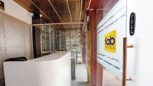 A hotel reception area with a modern design, including a reception desk, glass partitions, and a wooden ceiling. - Fabhotel 7 Am (Mumbai)