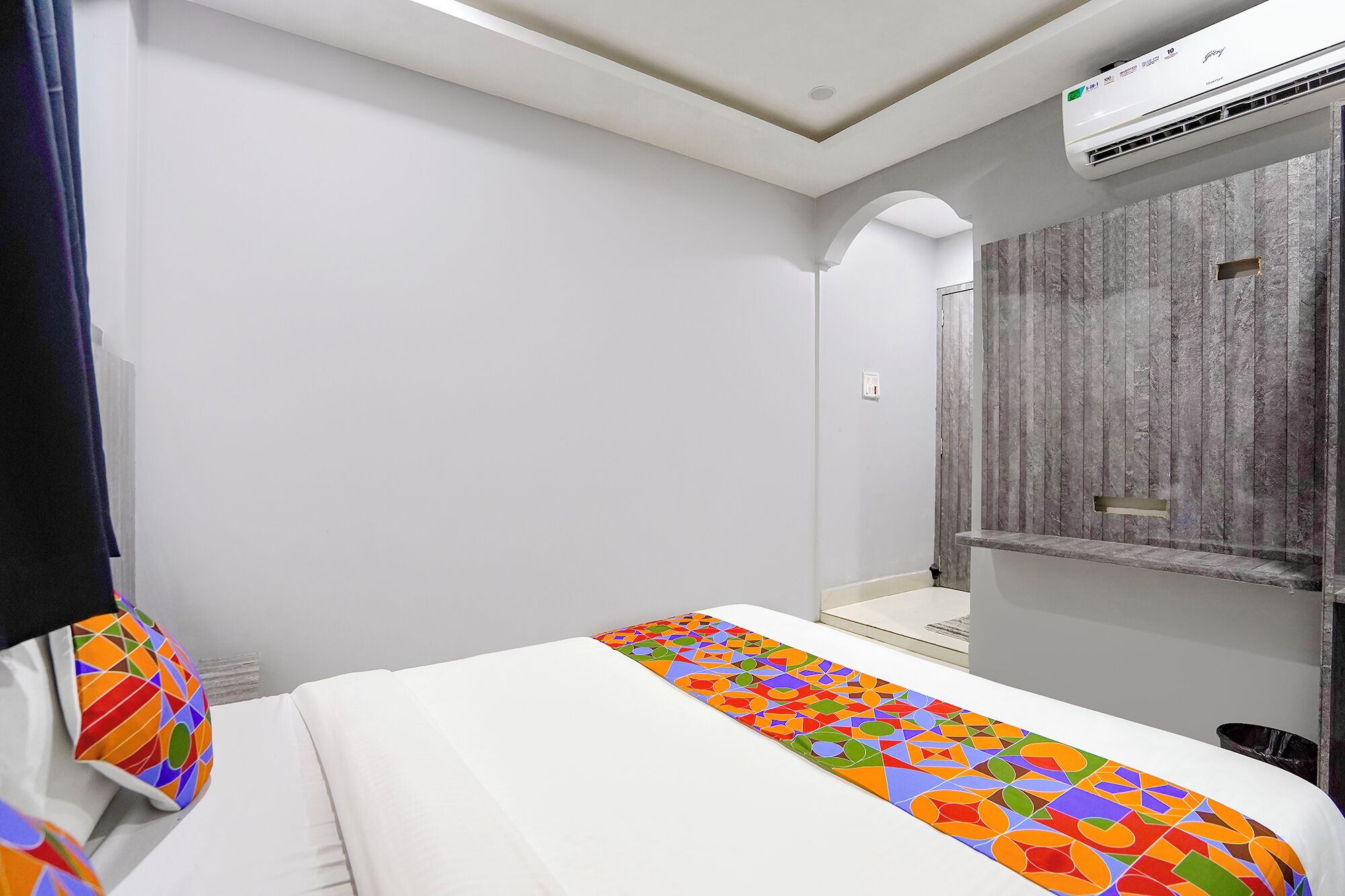 Hotellihuone, jossa on sänky, peili ja ilmastointilaite.