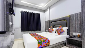 A modern hotel room with a large bed, a wooden headboard, a bedside table with a phone, and a TV mounted on the wall. - Fabhotel 7 Am (Mumbai)