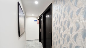 A hallway with a patterned wall, a framed picture on the left, and a door with a sign on the right. - Fabhotel 7 Am (Mumbai)