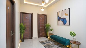 Um corredor moderno com duas portas de madeira, um banco azul-turquesa e uma pequena mesa com uma planta.