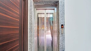 Um elevador com um visor digital exibindo '0' e uma porta de vidro.