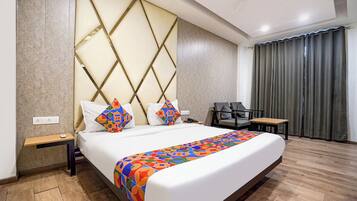 A modern hotel room with a large bed, a desk, and a chair.