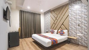 A modern hotel room with a large bed, a desk, and a wardrobe. - FabHotel Novis Stayz (Noida)