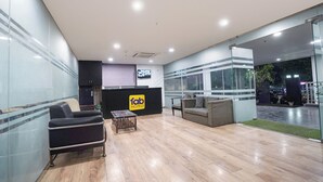 A hotel reception area with a reception desk, seating area, and a view of the parking lot. - FabHotel Novis Stayz (Noida)