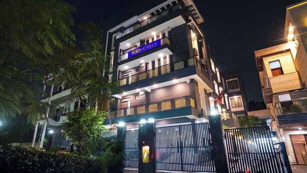 A multi-story hotel with balconies, a gated entrance, and a well-lit facade. - FabHotel Novis Stayz (Noida)