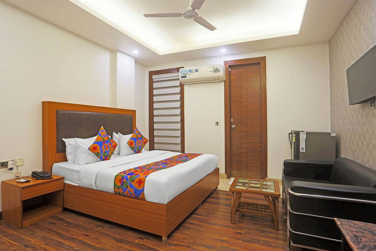 A hotel room with a bed, bedside table, chair, and a ceiling fan.