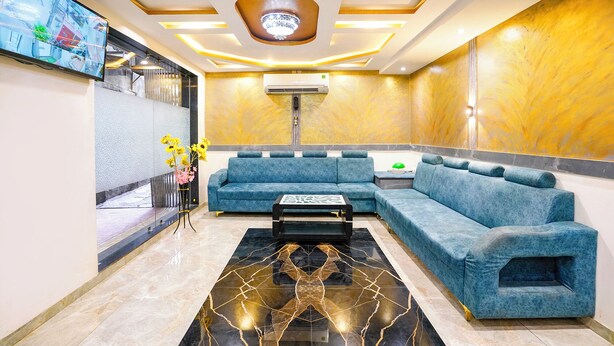 A modern lobby with a blue sectional sofa, a marble-patterned floor, and a ceiling with recessed lighting. - Fabhotel Bkc Annex (Mumbai)