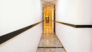 A modern hallway with marble flooring, black and gold accents, and a geometric ceiling design. - Fabhotel Bkc Annex (Mumbai)