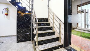 A staircase with black marble steps and metal railings, leading to a glass door with a metal handle. - Fabhotel Bkc Annex (Mumbai)