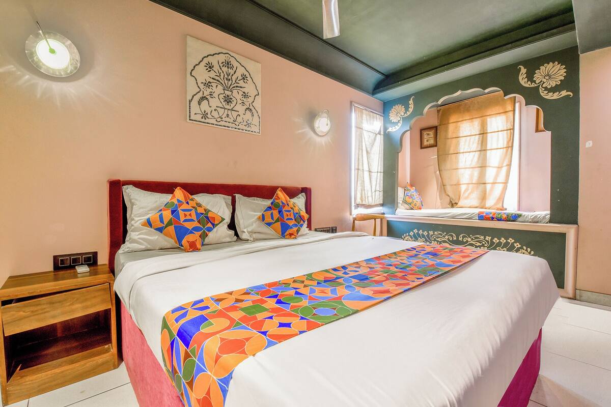 A bedroom with a bed, a nightstand, a mirror, and a wall with a floral design.