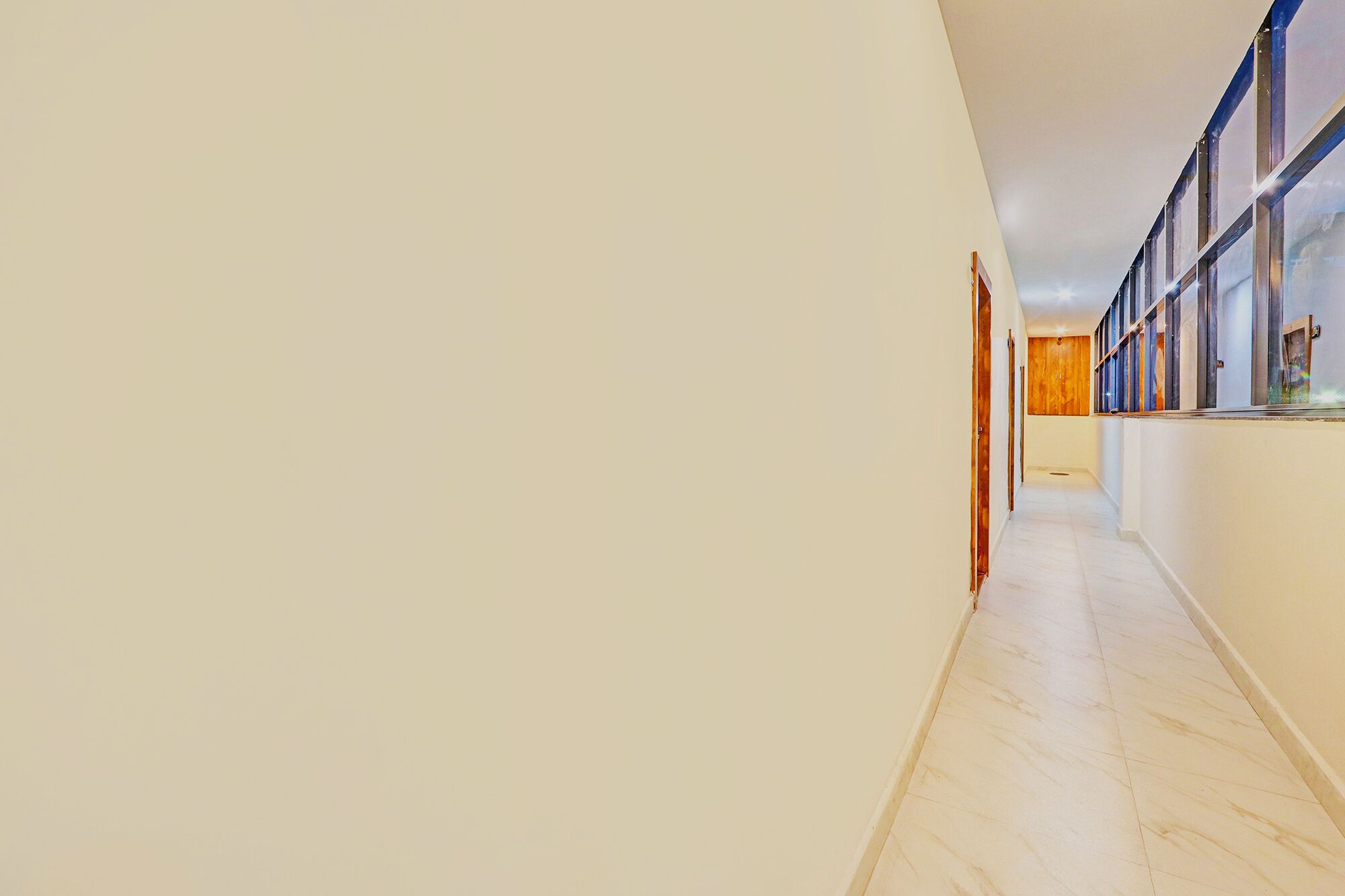 A modern interior with a long hallway, wooden flooring, and large windows.
