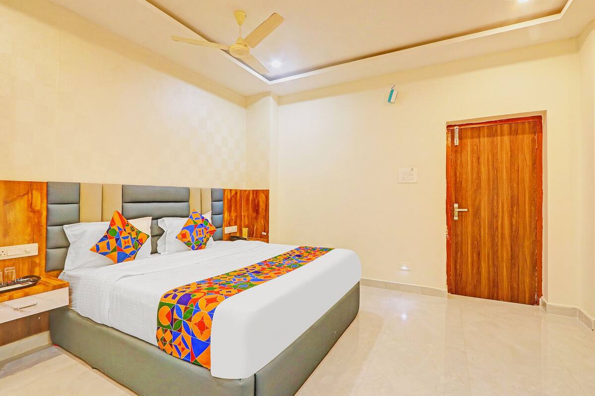 A bedroom with a bed, a nightstand, a wooden door, and a ceiling fan.