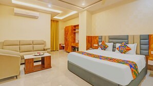 A hotel room with a bed, a sofa, a small table, a wardrobe, and a ceiling fan. - Fabhotel arjun residency - Near Kazipet junction railway station (Hanmakonda)