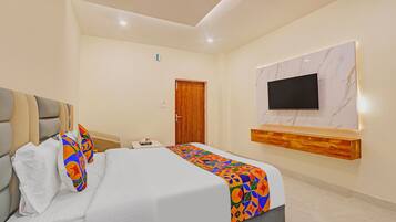 Una habitación de hotel con una cama, un televisor montado en la pared y una puerta de madera.
