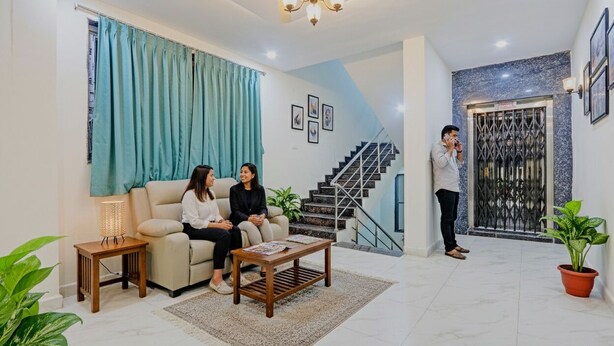 A living room with a sofa, coffee table, and a staircase. - Fabhotel arjun residency - Near Kazipet junction railway station (Hanmakonda)