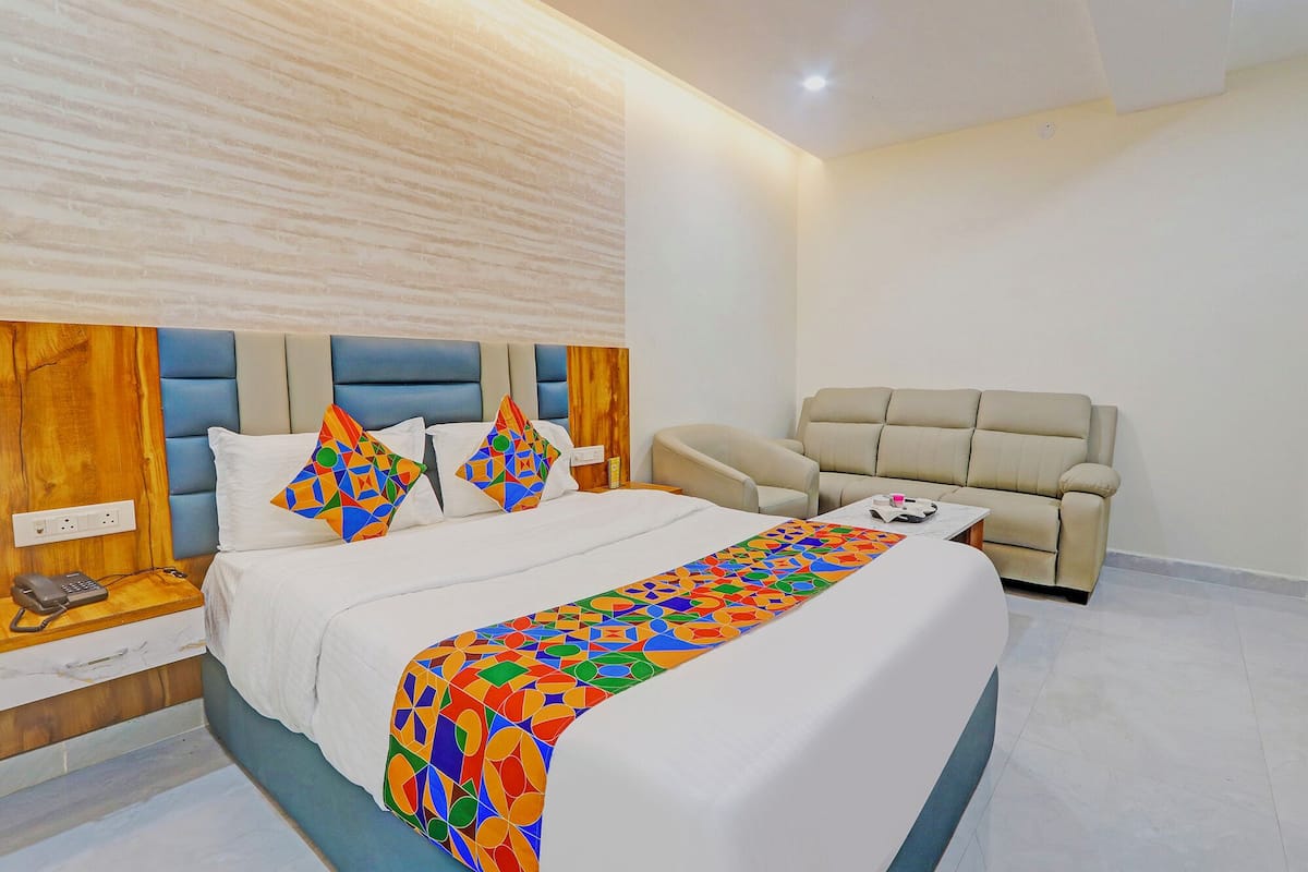 A hotel room with a bed, a sofa, and a bedside table with a phone.