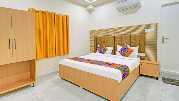 Una habitación de hotel con una cama de madera, un armario, un ventilador de techo y suelo de baldosas.