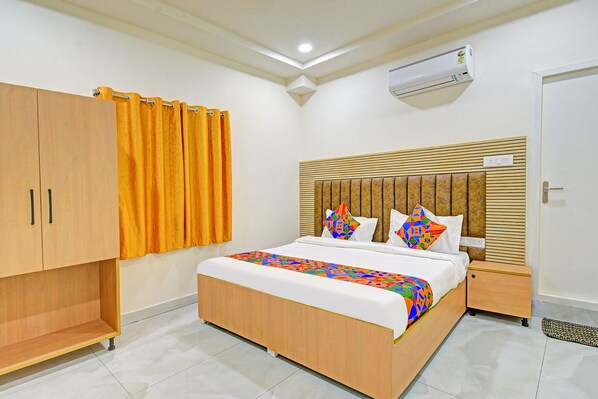 Una habitación de hotel con una cama de madera, un armario, un ventilador de techo y suelo de baldosas.