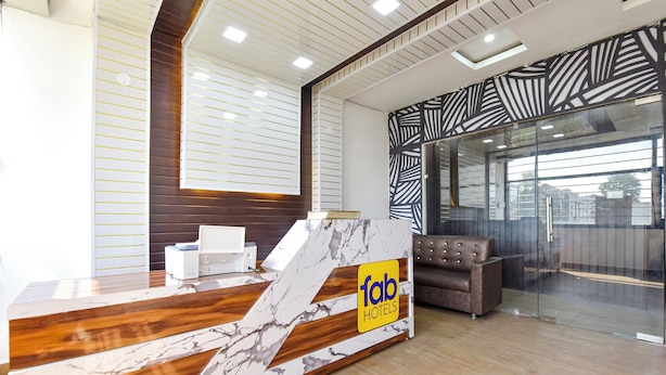 Balcão de recepção de hotel com design em mármore, um sofá e uma parede de vidro com vista.