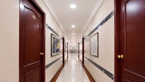 A corridor with wooden doors, marble walls, and framed artwork. - FabHotel Le Royal Inn - Nr Madras Medical Mission Hospital (Chennai)