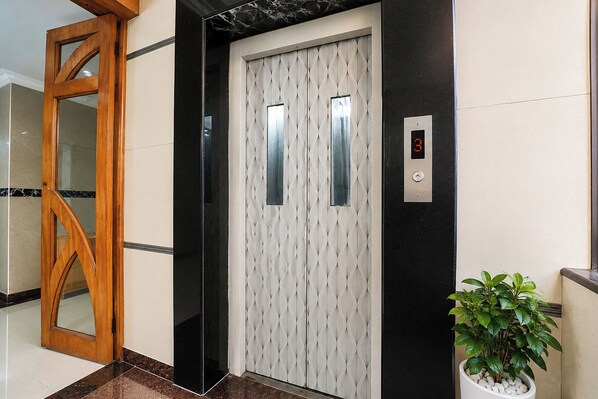 An elevator with a patterned door, a digital display, and a potted plant beside it. - FabHotel Le Royal Inn - Nr Madras Medical Mission Hospital (Chennai)