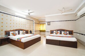A hotel room with two beds, a ceiling fan, an air conditioning unit, and a patterned wall. - FabHotel Le Royal Inn (Chennai)