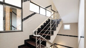 A staircase with metal railings, marble steps, and a small window at the top. - FabHotel Le Royal Inn - Nr Madras Medical Mission Hospital (Chennai)