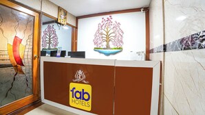 A reception desk with a logo, a decorative tree mural, and a mirror. - FabHotel Le Royal Inn - Nr Madras Medical Mission Hospital (Chennai)