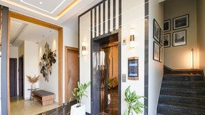 A modern hotel lobby with a marble floor, a wooden bench, potted plants, a staircase, and framed pictures on the walls. - Fabhotel K9 Pearl (Ludhiana)