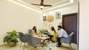 A room with a ceiling fan, a table with chairs, and a potted plant. - Fabhotel K9 Pearl (Ludhiana)