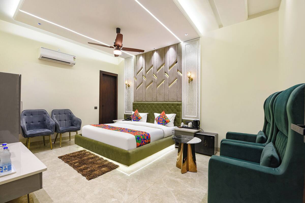 Una habitación de hotel moderna con una cama grande, dos sillones, una mesita y un ventilador de techo.