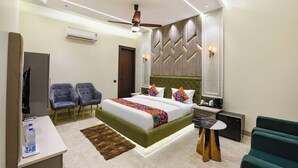 A modern hotel room with a bed, two chairs, a small table, a sofa, and a ceiling fan. - Fabhotel K9 Pearl (Ludhiana)