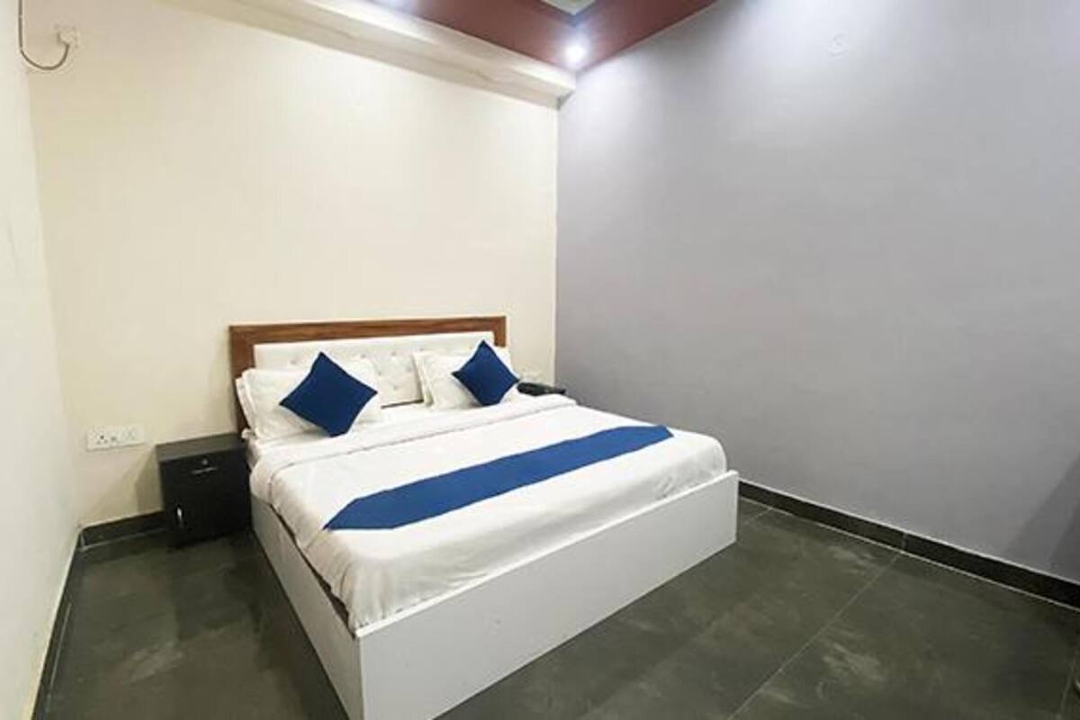 A single-bed room with a wooden headboard, white bedding, and a blue accent.