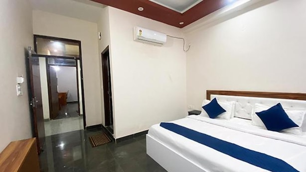 Een hotelkamer met een bed, nachtkastje, spiegel en een deur die naar een andere kamer leidt.