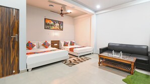 A modern living room with two white sofas, a black sofa, a wooden coffee table, and a ceiling fan. - Fabhotel Sr Grand (Lucknow)