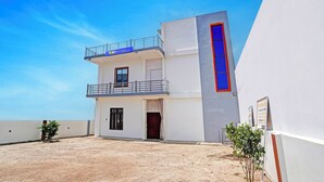 Un edificio de dos pisos con un balcón en el nivel superior, una entrada pequeña y un cartel que indica un número de habitación.