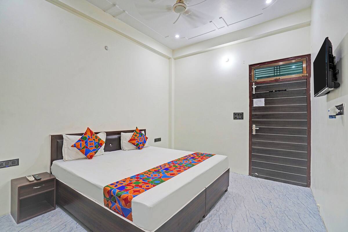 Habitació d'hotel amb llit, taules de nit, televisió penjada a la paret i porta amb finestreta.