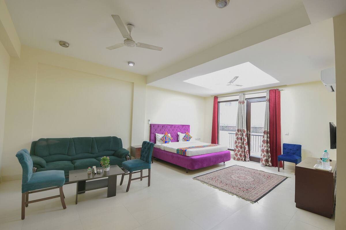 A spacious living area with a green sofa, a coffee table, and a purple bed with a view to the outside.